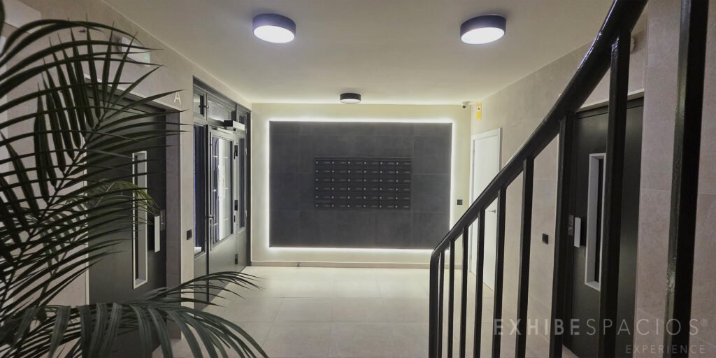 Detalle de vestíbulos de después de la obra Pared de los buzones del vestíbulo de Carrer Eduard Marquina, Badalona: porcelánico arena volcánica, envolvente con luz indirecta y 36 buzones